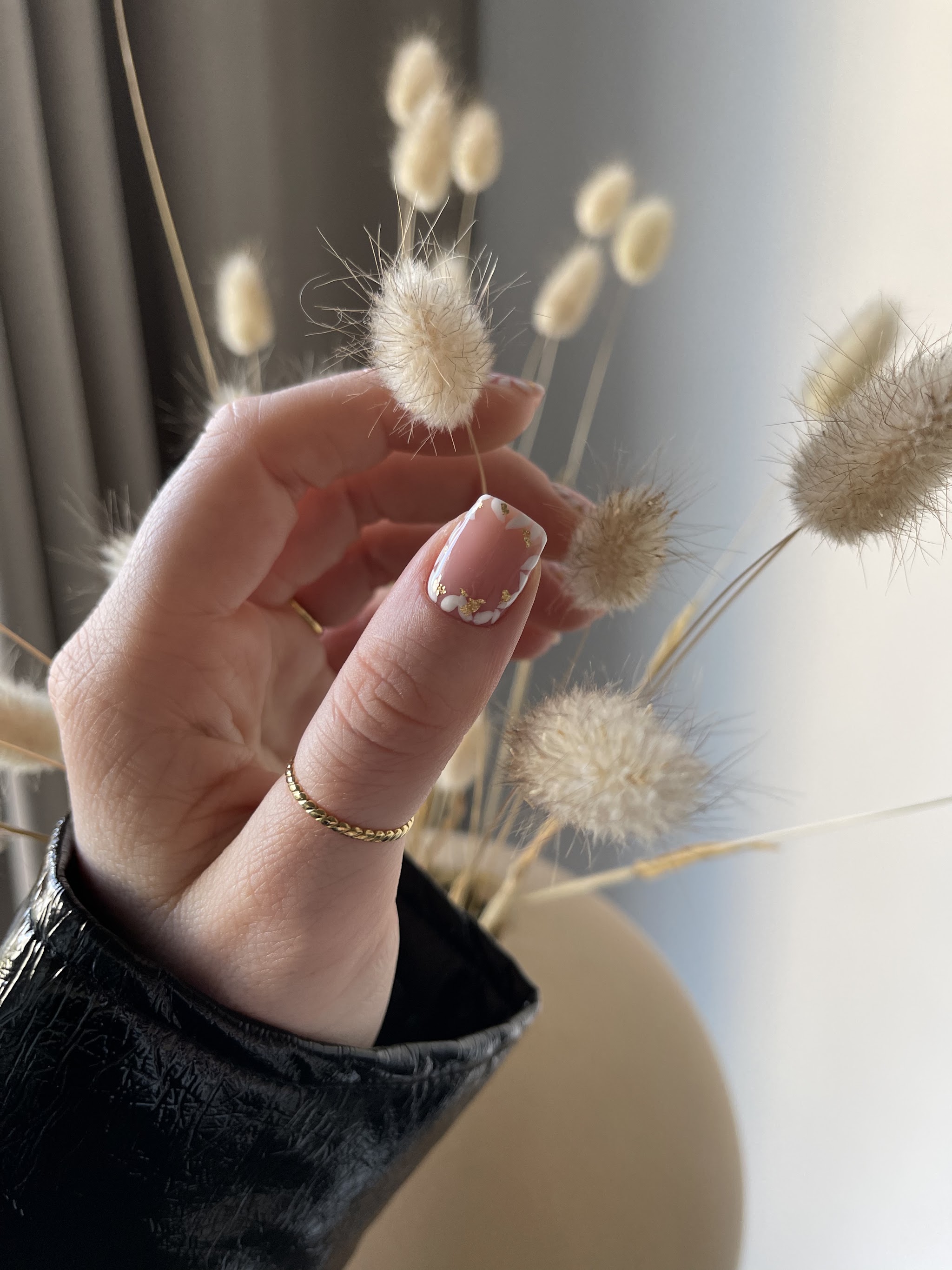 Hand met verzorgde nagels en een sierlijk detail, met gedroogd pampasgras
